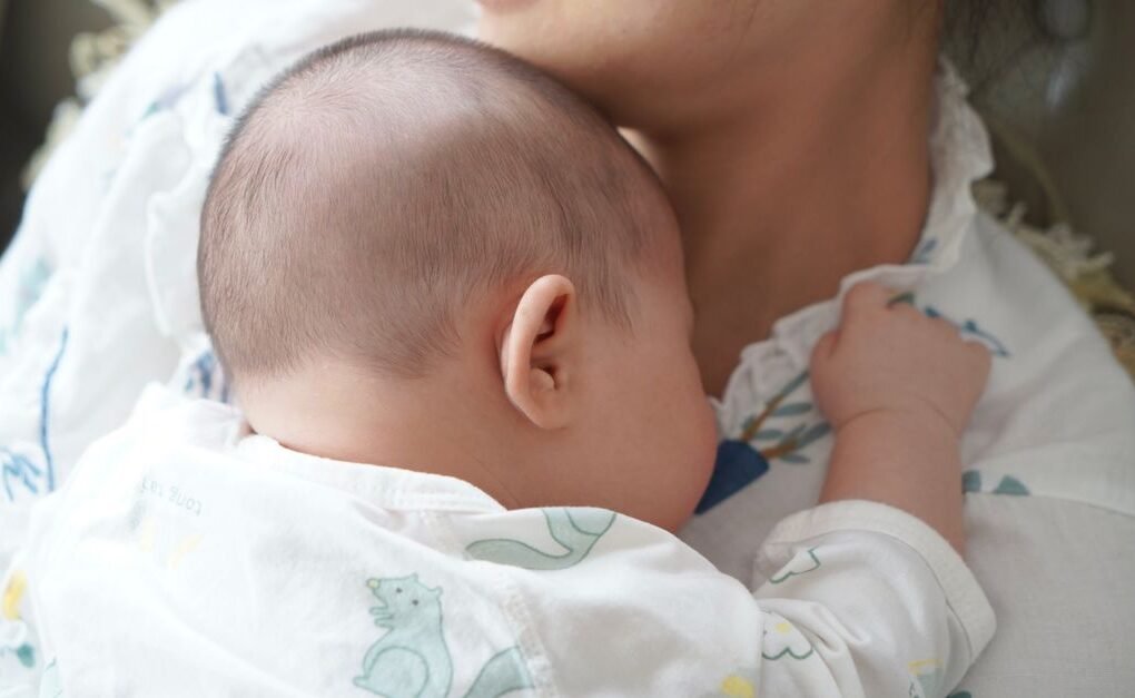 A newborn baby peacefully sleeps on the mother's chest, capturing a tender moment of love and comfort.