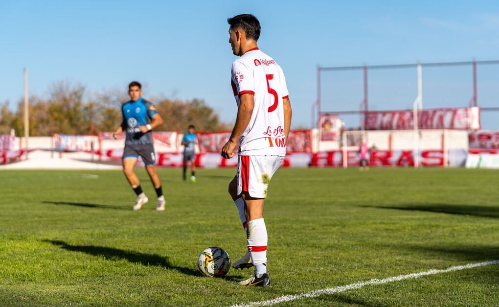 Soccer player in action during a daytime match on a sunny outdoor field.