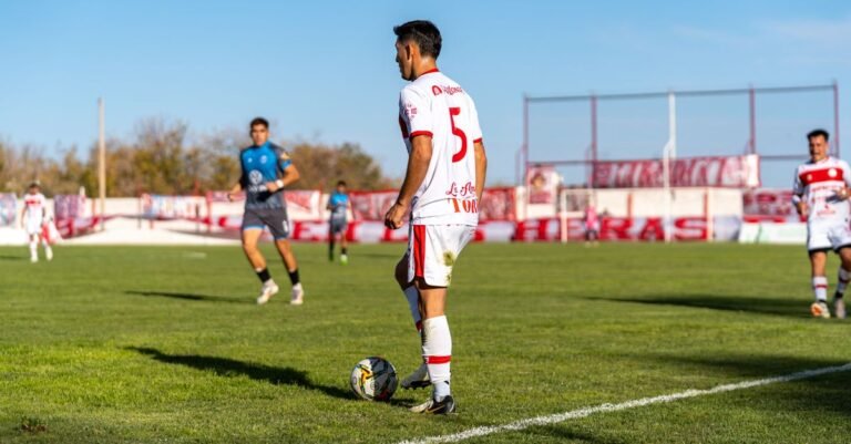 Soccer player in action during a daytime match on a sunny outdoor field.