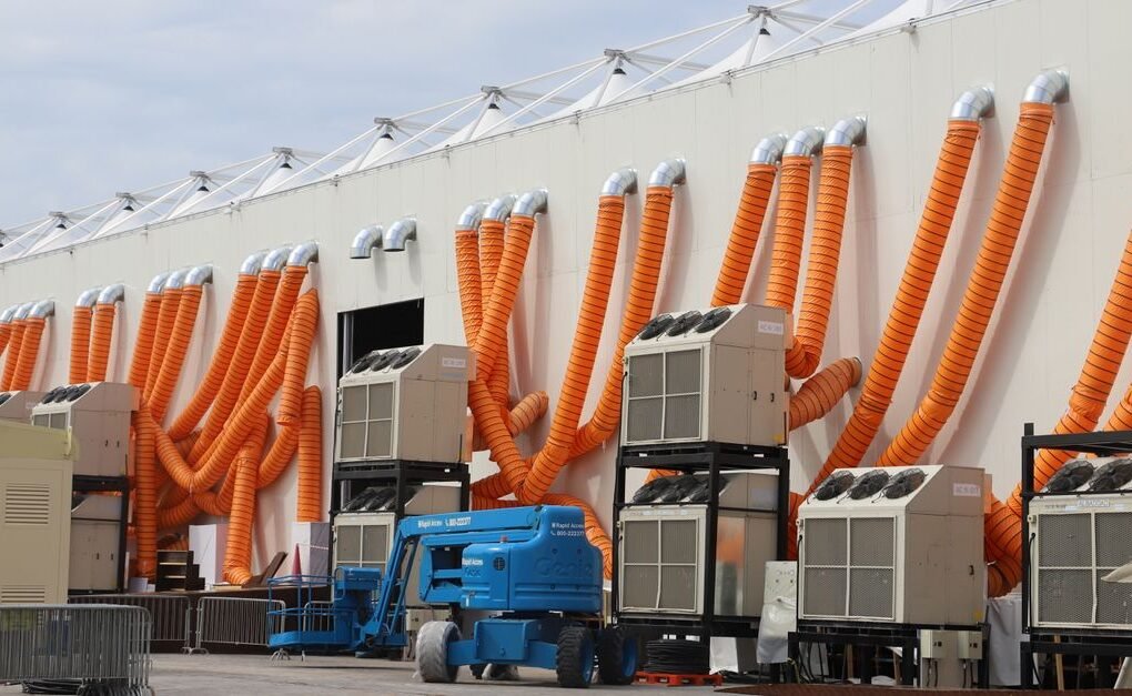 Modern industrial cooling units with striking orange ducts outside a building.