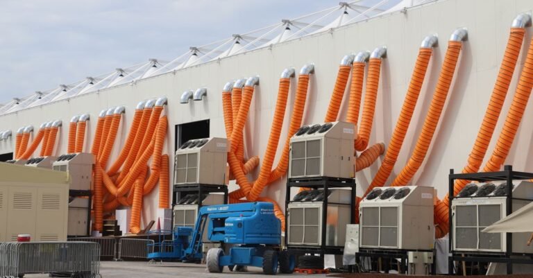 Modern industrial cooling units with striking orange ducts outside a building.